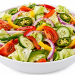 A vibrant garden salad bowl filled with crisp greens, seasoned fried paneer or tofu cubes, broccoli, sliced cheese, tomatoes, cucumbers, bell peppers, red onions, and pickled jalapeños.